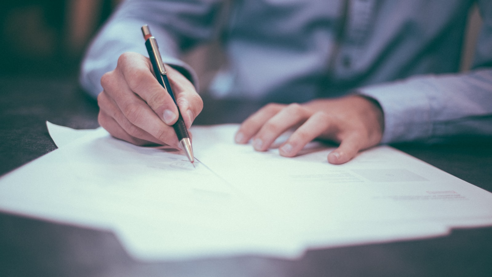Assinatura de contrato em papel, cláusula e caneta